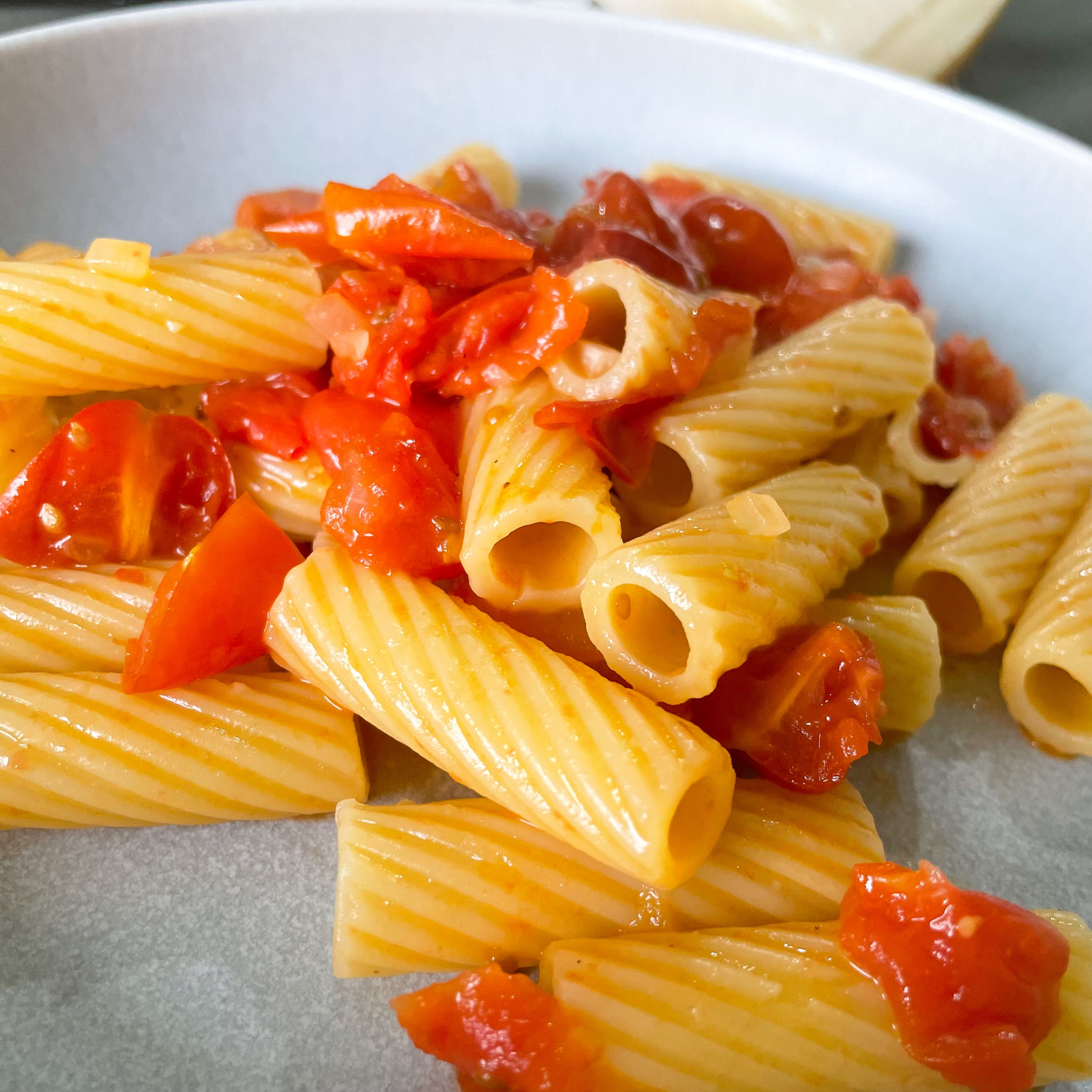 Nudeln in einer Sauce auf Tomaten, Zwiebeln und Honig, dazu Parmesan