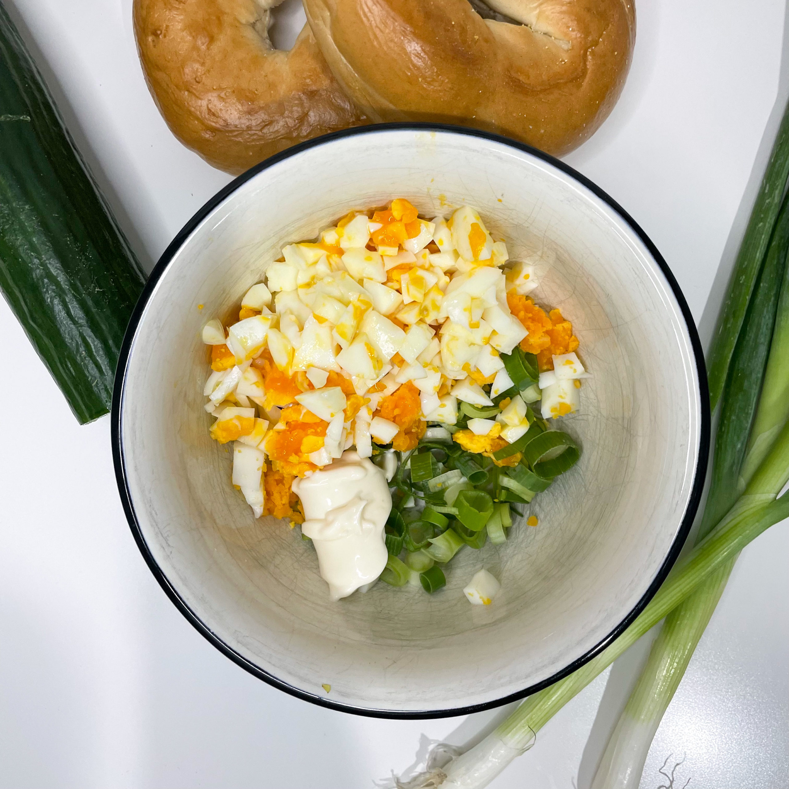 vegetarisch belegter Bagel mit Gurke, Ei und Frühlingszwiebel